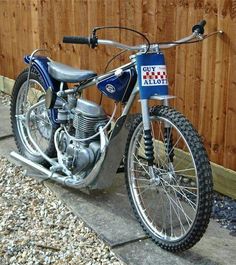 a blue motorcycle parked next to a wooden fence