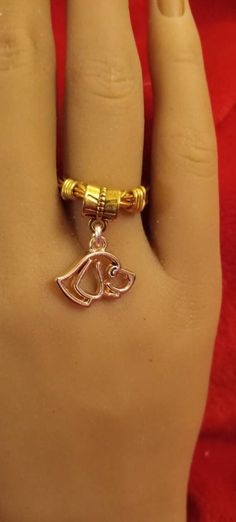 a person's hand with a gold ring on it and a dog head charm