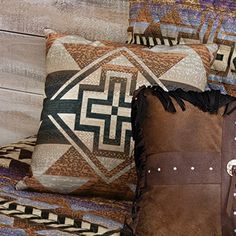 two decorative pillows sitting on top of a couch next to a wooden headboard and wall