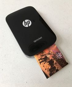 a hp printer sitting on top of a table next to a small piece of paper