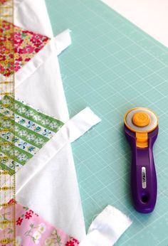 a pair of scissors sitting on top of a piece of fabric next to a sewing needle