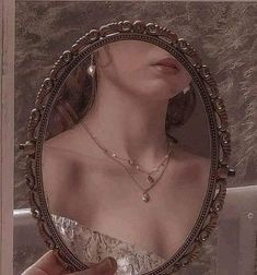 a woman's reflection in a mirror with jewelry on her neck and necklaces around her neck