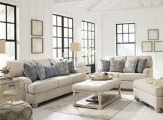 a living room filled with furniture and lots of windows in the wall behind it is a coffee table