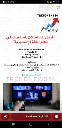 a person holding a cell phone in front of a tv with arabic writing on it