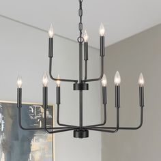 a black chandelier with six lights hanging from it's center, in a living room