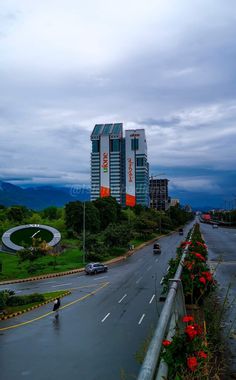 a city street with tall buildings in the background and flowers on the side of the road