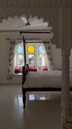 a bed sitting in the middle of a room with white walls and curtains on it