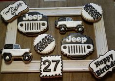 decorated cookies in the shape of jeeps and cars are displayed on a wooden frame