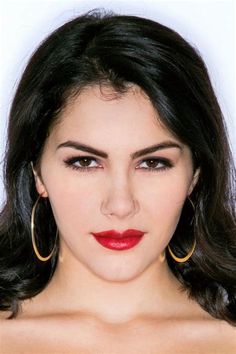 a woman with long black hair wearing large hoop earrings and red lipstick on her face