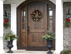 two planters with wreaths on the front door