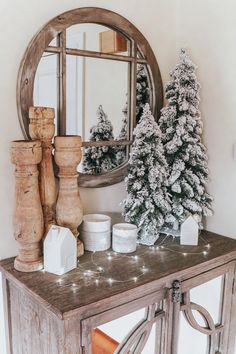 a small christmas tree sitting on top of a wooden table next to a round mirror