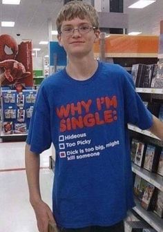 a young man standing in front of a book shelf wearing a blue t - shirt that says why i'm single