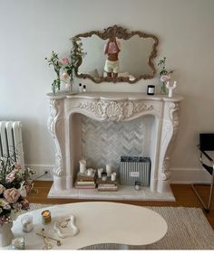 a living room with a white fireplace and flowers on the table in front of it