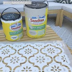 two cans of sandtex sitting on top of a table next to a chair