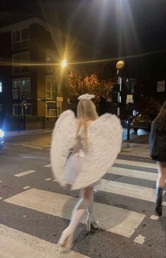 a woman dressed as an angel crossing the street