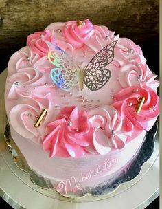 a cake with pink frosting flowers and a butterfly on top is sitting on a plate