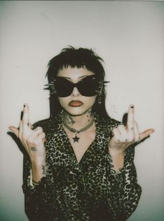 a woman wearing sunglasses and holding up two fingers