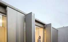 a woman walking out of an open door into a room filled with metal containers and doors