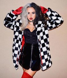 a woman with grey hair wearing a black and white checkerboard jacket, red knee high boots