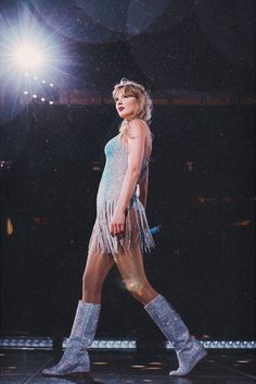 a woman is walking down the runway wearing boots and fringed clothing with her legs spread out