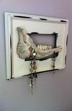 an animal's skull mounted to the side of a wall with beads hanging from it