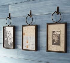 three framed pictures hanging on the wall with metal rings attached to each one's sides