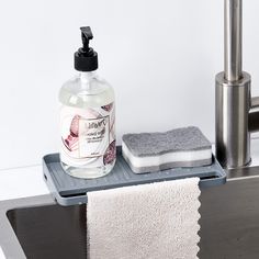 a bottle of hand soap sitting on top of a sink next to a towel rack