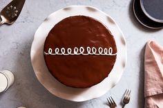 a chocolate cake sitting on top of a white plate next to silverware and utensils