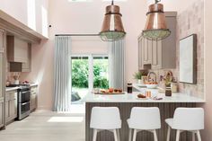 three white chairs are in front of a kitchen island with two pendant lights hanging over it