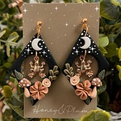 the earrings are decorated with flowers, leaves and crescents on black acrylic