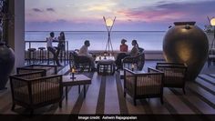 people are sitting at tables on the balcony overlooking the water and ocean with large vases