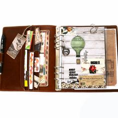 an open brown leather wallet with various items in it and a notepad attached to the pocket