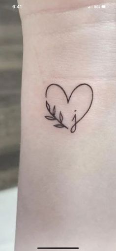 a small tattoo on the wrist of a woman with a heart and an arrow in it