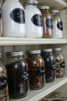 several jars with labels on them are lined up in a pantry shelf next to each other