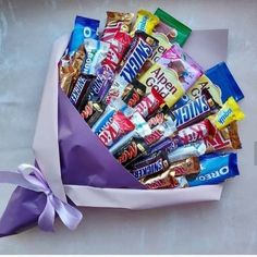 a purple bag filled with assorted candy bars and a bow tied around the top