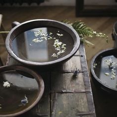 an old wooden table topped with dishes filled with water and flowers on top of it