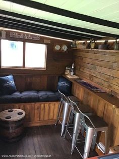 the inside of a small cabin with wood paneling and barstools in it