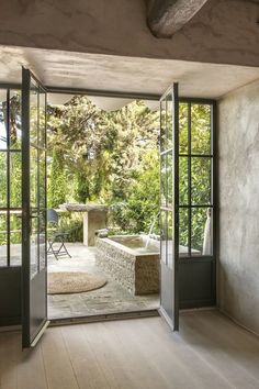 an open door leading to a patio with a hot tub in the middle and trees outside