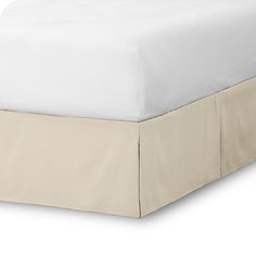 a bed with a white bedspread and a beige skirt on top of it