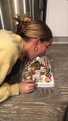 a woman bending over to look at a decorated cake on the floor in front of her