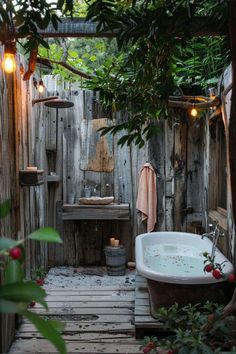 a bathtub in the middle of a wooden fence with lights hanging from it's sides