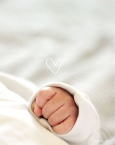 a close up of a baby's hand with a heart drawn on the background