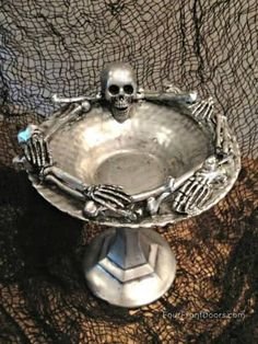 a silver bowl with skeleton hands on it