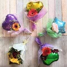 four bouquets of flowers wrapped in cellophane and tied with ribbons on a wooden surface