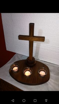 a wooden cross with three votives in front of it