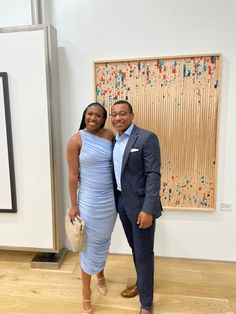 a man and woman posing for a photo in front of an art work on display