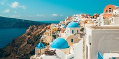 an aerial view of the blue and white buildings in oia, with water in the background