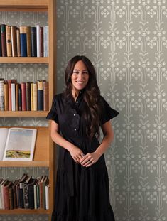 a woman standing in front of a bookshelf