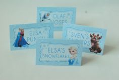 three frozen princess place cards on a white surface with snowflakes in the background