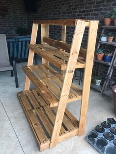 a wooden shelf sitting on top of a cement floor next to potted planters